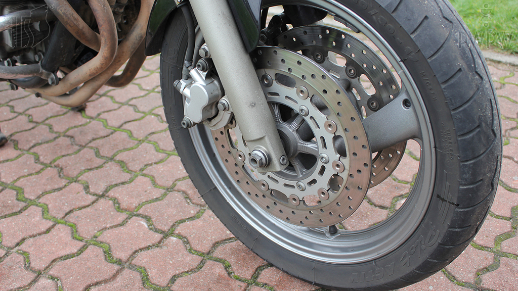 Pytanie Q-1123: Co może osłabić działanie układu hamulcowego przedniego koła motocykla?
